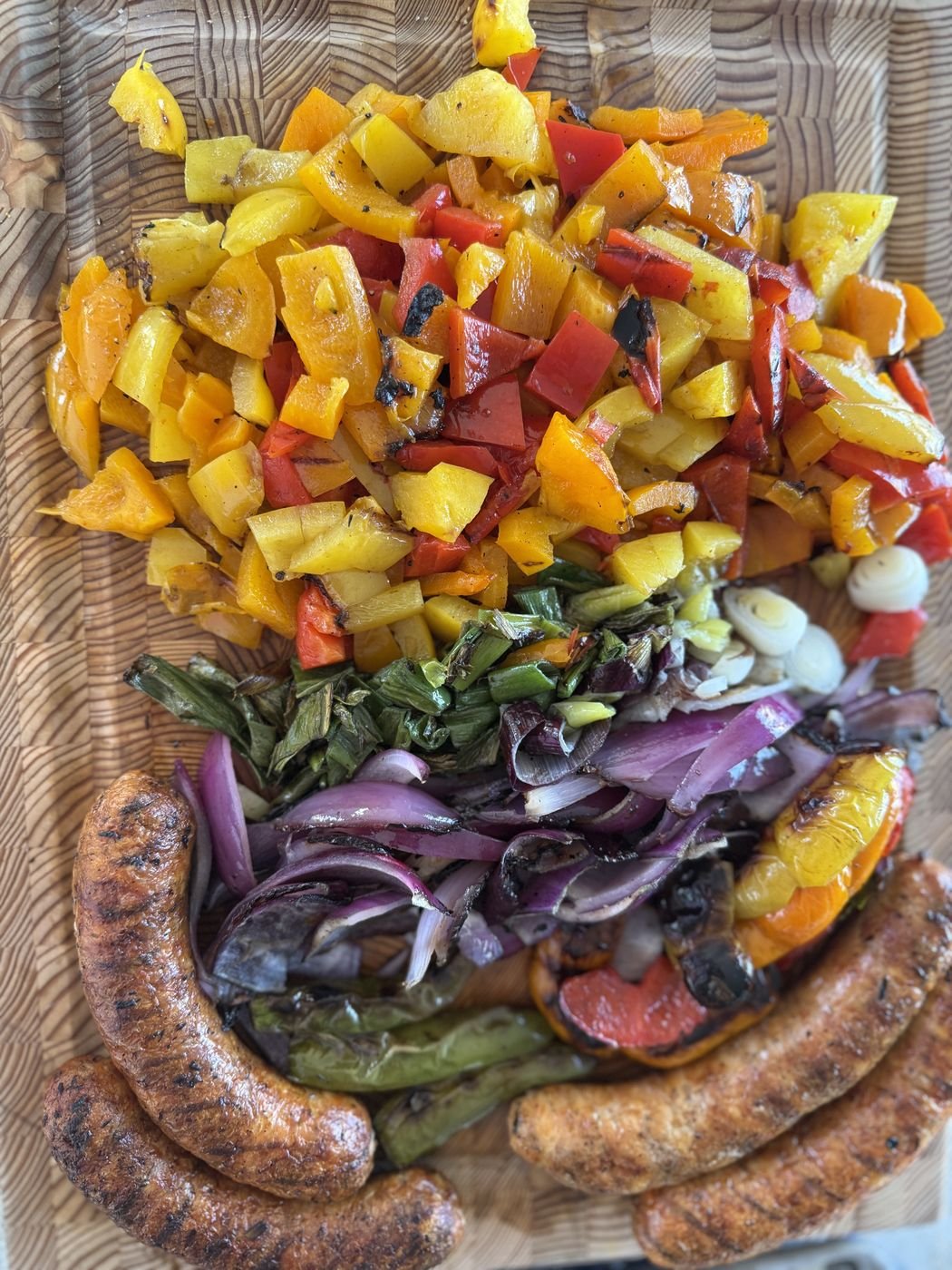 A board of charred peppers, red onions and grilled sausages