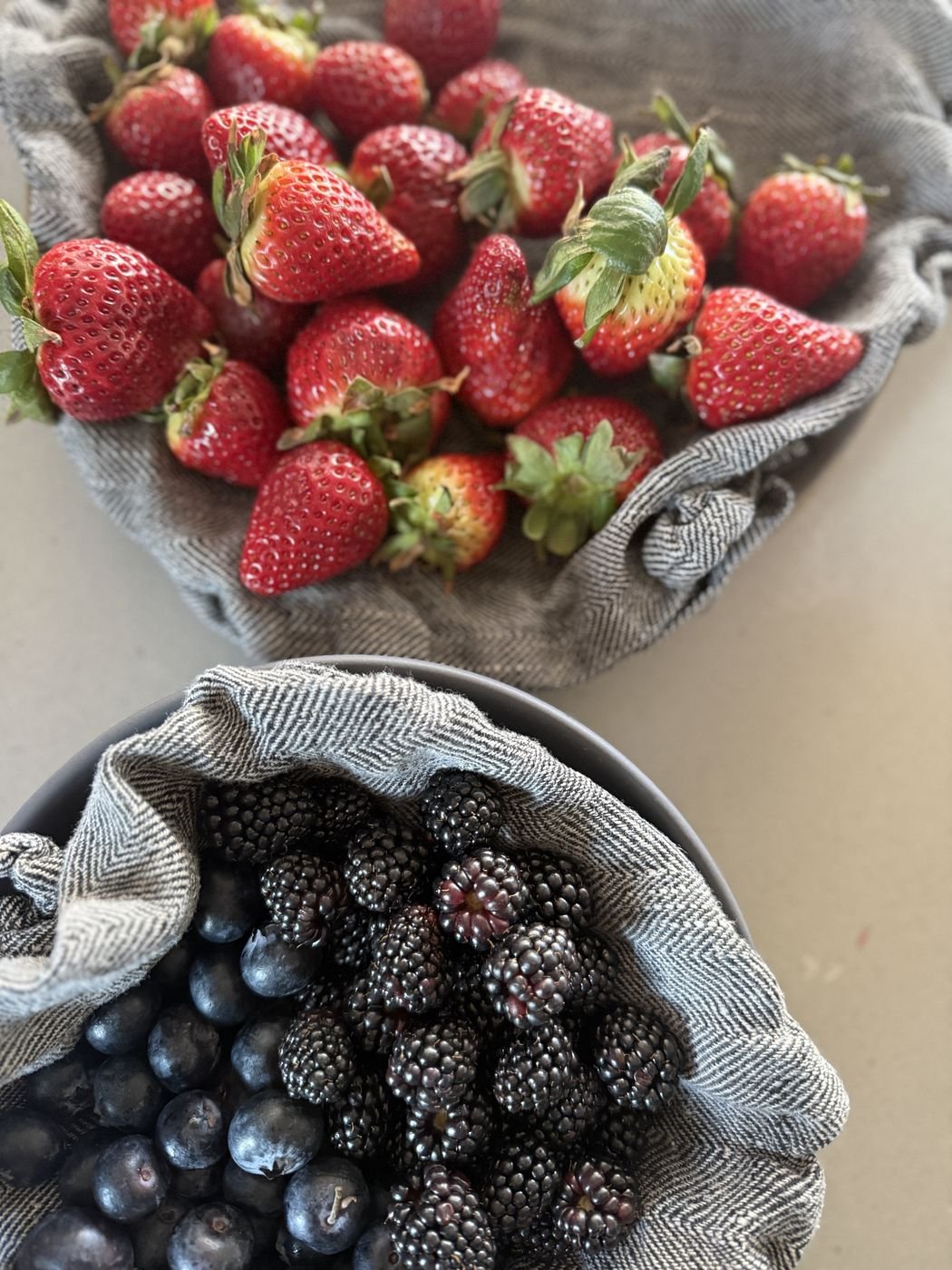 Strawberries, blackberries and blueberries in linen-lined bowls